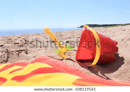 Colorful beach toys and towel in the sandy shores of Panmure Island in Prince Edward Island, Canada