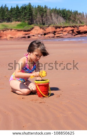 Little girl playing in the sand with toys at Cabot Beach, Prince Edward Island, Canada