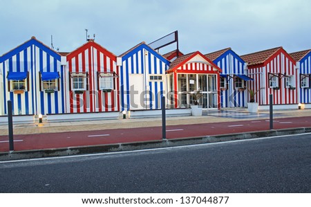 Costa Nova colorful striped hut like architecture in, red, and blue of the Beiras, Portugal, Europe in the evening under cloudy sky