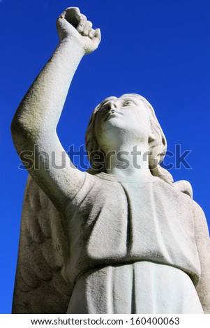 Statue of Angel looking towards the sky or heaven with arm raised up in faith or hope, at a cemetery in Montreal, Quebec