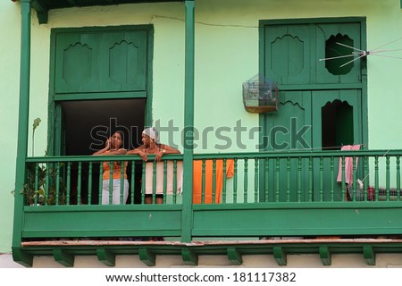 HAVANA,CUBA-FEBRUARY 22, 2014: Two Cuban women stand on their balcony in an old town square in Havana, Cuba, February 22, 2014