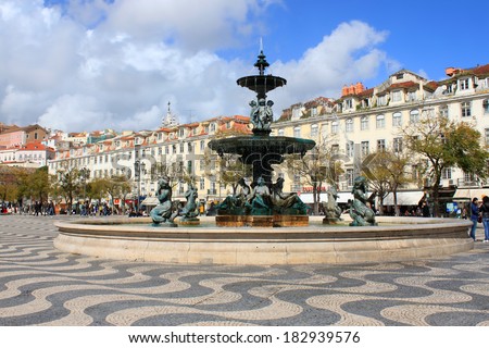 LISBON, PORTUGAL - MARCH 25, 2013: Rossio Square showing fountain, buildings with shops, and people, a gathering place for both tourists and Lisboners alike, in Lisbon, Portugal, on March 25, 2013