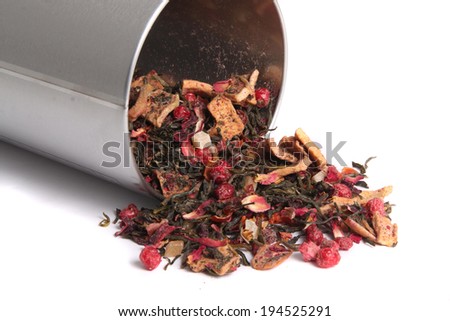 Dried loose mixed berry and green leaf tea tea spilling out of a tin ready to steep and brew on a white background