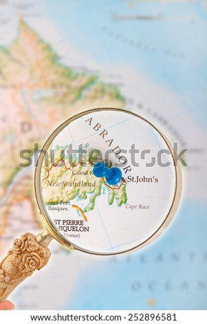 Blue tack on map of Canada with magnifying glass looking in on St. John\'s Newfoundland in the Maritme provinces in Eastern Canada