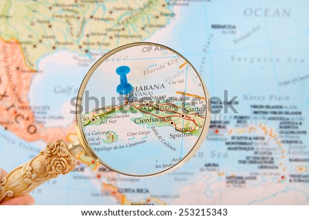 Blue tack on map of Caribbean with magnifying glass looking in on Havana or Habana, Cuba