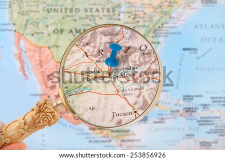 Blue tack on map of United States of America with magnifying glass looking in on Phoenix, Arizona
