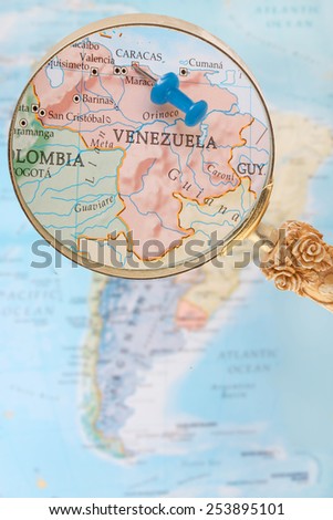 Blue tack on map of South America with magnifying glass looking in on Caracas, Venezuela