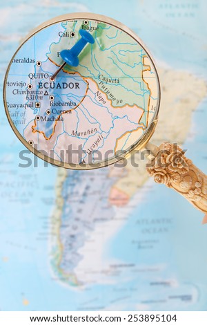 Blue tack on map of South America with magnifying glass looking in on Quito, Ecuador