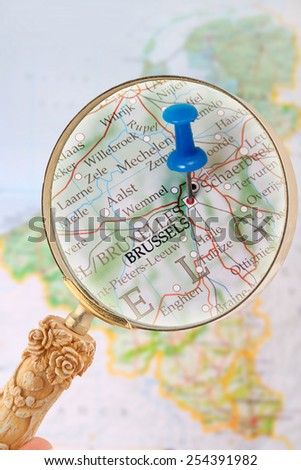 Blue tack on map of Benelux with magnifying glass looking in on Brussels, Belgium