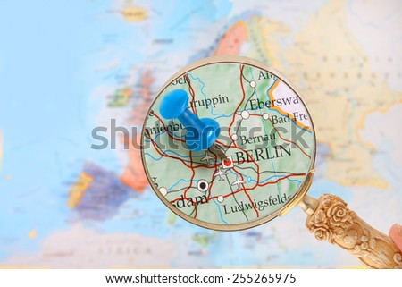Blue tack on map of Europe with magnifying glass looking in on Berlin, Germany