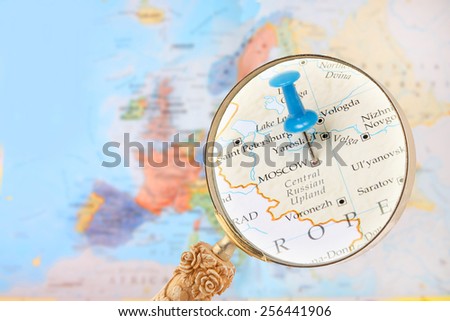 Blue tack on map of Europe with magnifying glass looking in on Moscow, Russia