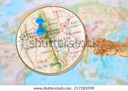 Blue tack on map of the world with magnifying glass looking in Jerusalem, Israel in the Middle East, Asia