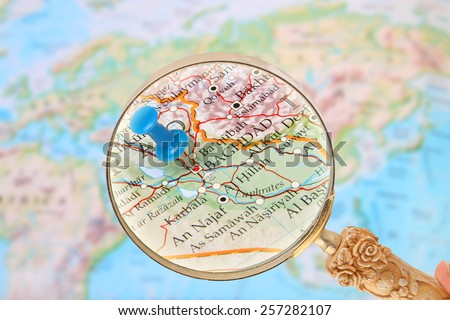 Blue tack on map of  the world with magnifying glass looking in on Baghdad, Iraq, Middle East in Asia