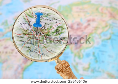 Blue tack on map of the world with magnifying glass looking in on Minsk, Belarus