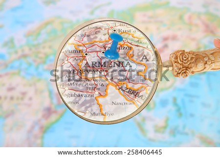 Blue tack on map of the world with magnifying glass looking in on Yerevan, Armenia