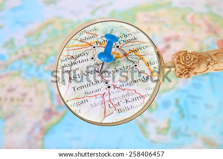Blue tack on map of the world with magnifying glass looking in on Astana, Kazakhstan