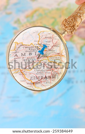 Blue tack on map of Africa with magnifying glass looking in on Lusaka, Zambia