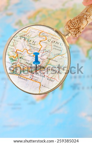 Blue tack on map of Africa with magnifying glass looking in on Kinshasa, Democratic Republic of Congo