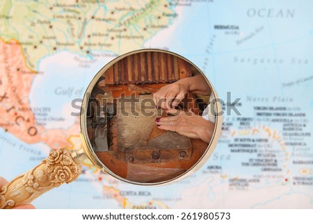Looking in on a woman making cigars in Cuba with a map of the Caribbean