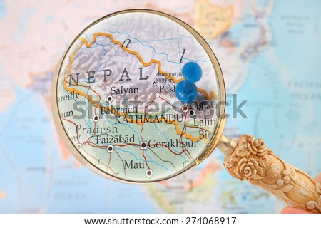 Looking in on Kathmandu, Nepal with a magnifying glass and a blurred map of Asia in the background