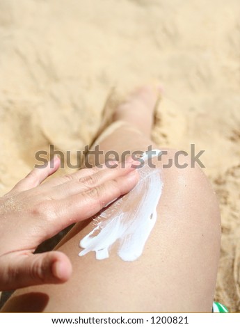 applying suntan lotion on leg (focus is on hand and cream)
