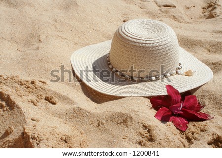 beach hat and flower in the sand