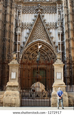 man reads information at the entrace gates of The Cathedral in Seville, Spain