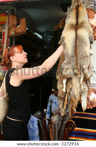 woman touches pelts at a store with concern on her face