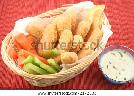 basket of crispy chicken fingers with platter of vegetables and dip