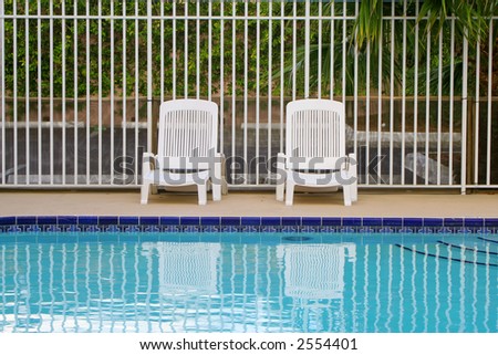 white plastic loungers along the fence on a pool deck