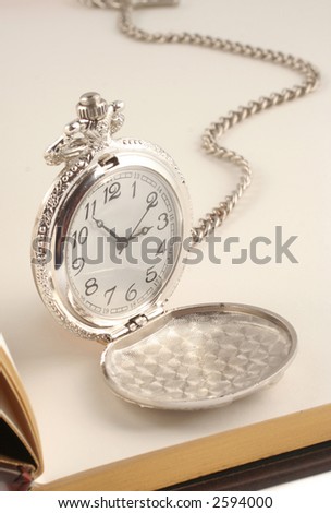 antique silver  pocket watch on top of blank book
