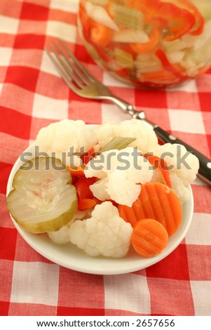 variety of pickled vegetables and pickle jar in background