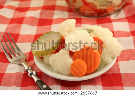 variety of pickled vegetables and pickle jar in background