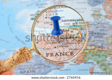 magnifying glass over Paris, France map with destination tack