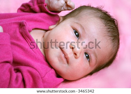small one week old newborn baby on a pink background