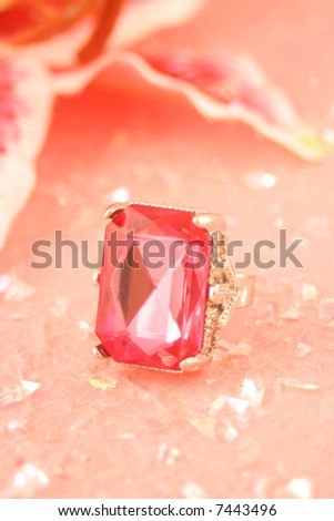large pink stone engagement ring on pink background surrounded by glitter