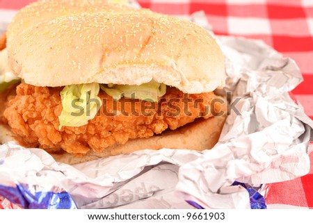 fast food crispy chicken burger still in wrapper with checkered red background