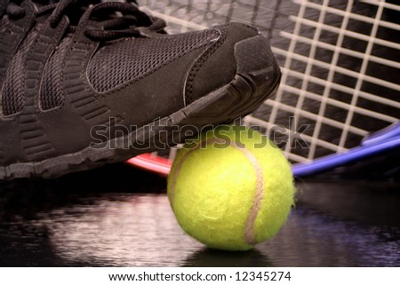 black sports sneaker on green tennis ball with raquet in the background