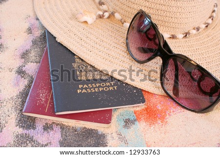 passports on beach towel and sand with hat and sunglasses depicting summer or tropical travel
