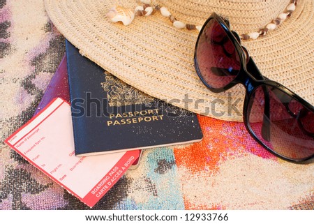 passports on beach towel and sand with hat and sunglasses depicting summer or tropical travel with blank boarding pass