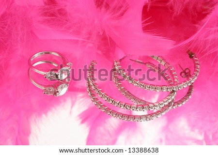glamorous diamond ring and earring on vanity mirror with a pink feather boa in the background