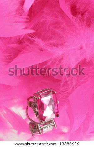 glamorous diamond ring on vanity mirror with a pink feather boa in the background