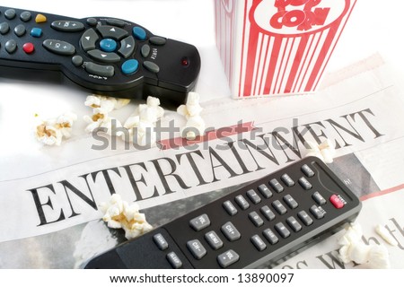 entertainment section of the newspaper with television remote controls and popcorn