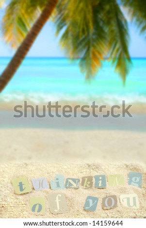 thinking of you on a mound of sand on a tropical beach with palm tree and ocean in the background