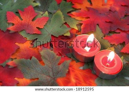 tea light candles on an autumn leaf background in orange, red, and green