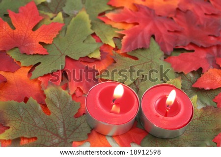 tea light candles on an autumn leaf background in orange, red, and green