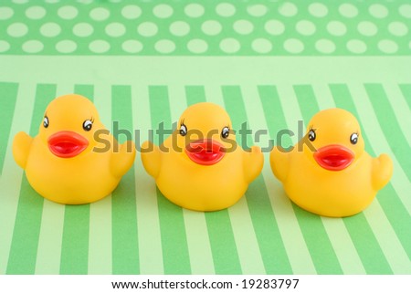 three child's rubber duck on top of green  striped background ready for bath time