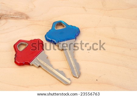 red and blue house keys laying on a wood background