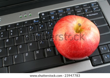 a business laptop with shiny red apple depicting workplace wellness or healthy school lunch