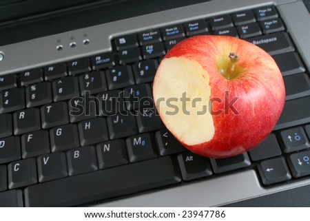 a business laptop with shiny bitten red apple depicting workplace wellness or a healthy school snack